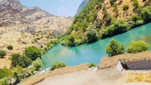 تُعد دهوك، المدينة الجبلية الساحرة في شمال العراق، واحدة من أجمل الوجهات السياحية لقضاء عطلة صيفية في 2025. تجمع هذه المدينة بين الطبيعة الخلابة، الأجواء المعتدلة، والمعالم الثقافية والتاريخية، مما يجعلها خيارًا مثاليًا للعائلات، الأزواج، ومحبي المغامرات. من الشلالات المتدفقة إلى المصايف الهادئة والبحيرات الطبيعية، تقدم دهوك تجربة سياحية متنوعة تناسب جميع الأذواق. تتميز دهوك بسهولة الوصول إليها، خاصة للمسافرين من داخل العراق، حيث يمكن الوصول إليها عبر مطار أربيل الدولي، ثم السفر برًا في رحلة ممتعة عبر المناظر الطبيعية. مع همين تور، يمكنك الاستمتاع برحلة صيفية خالية من التعقيدات، سواء عبر كروبات سياحية منظمة أو خطط سفر فردية مصممة حسب رغبتك. في هذا الدليل الشامل، نأخذك في جولة بين أجمل الأماكن السياحية في دهوك لصيف 2025، مع نصائح عملية مقدمة من همين تور لضمان تجربة سفر لا تُنسى. لماذا تختار دهوك في الصيف؟ تتميز دهوك في الصيف بأجوائها المعتدلة مقارنة بباقي مدن العراق، حيث تتراوح درجات الحرارة بين 20 و30 درجة مئوية في المناطق الجبلية. توفر المدينة مزيجًا فريدًا من المناظر الطبيعية الخلابة، من الجبال الخضراء إلى الوديان العميقة والشلالات، بالإضافة إلى التراث الثقافي الكردي الغني. سواء كنت تبحث عن الاسترخاء، التخييم، أو استكشاف المعالم التاريخية، فإن دهوك تقدم تجربة سياحية متكاملة. مع همين تور، يمكنك التخلص من عبء التخطيط والاستمتاع برحلة مريحة تشمل الإقامة، النقل، والجولات السياحية، مما يتيح لك التركيز على استكشاف سحر دهوك. خدمات همين تور لتجربة سفر مثالية تقدم همين تور حلولاً سياحية شاملة لزيارة دهوك، تشمل: الإقامة: خيارات فنادق وشاليهات تناسب جميع الميزانيات، من الفنادق الفاخرة إلى الأكواخ الريفية. النقل: تنقلات مريحة من مطار أربيل إلى دهوك، مع خيارات السيارات الخاصة أو الحافلات السياحية. جولات سياحية: برامج يومية بصحبة مرشدين محترفين لاستكشاف أجمل معالم دهوك. أنشطة متنوعة: من التخييم ورحلات المشي إلى جلسات الشواء وتجارب تذوق الأطعمة المحلية. يمكنك حجز رحلتك بسهولة عبر تطبيق همين تور أو الموقع الإلكتروني، مع إمكانية تخصيص خطة السفر حسب اهتماماتك. أجمل الأماكن السياحية في دهوك لصيف 2025 نقدم لك ست وجهات سياحية رائعة في دهوك، تجمع بين الطبيعة الخلابة، الهدوء، والمغامرة. 1. مصيف كلي بالندا: ملاذ الطبيعة الهادئ يقع مصيف كلي بالندا في قضاء العمادية، وهو واحد من أجمل المصايف في دهوك. يتميز بوادٍ عميق تحيط به الجبال من كل جانب، مع أشجار كثيفة ومياه باردة تتدفق بين الصخور. المصيف مثالي للنزهات العائلية، جلسات الشواء، والتصوير الفوتوغرافي، خاصة في الصيف حيث تكون المناظر خضراء والأجواء منعشة. نصيحة من همين تور: احجز جولة إلى كلي بالندا مع همين تور للاستمتاع بنزهة مريحة مع مرشد يشرح جمال المنطقة وتاريخها الطبيعي. 2. مصيف شرانش: جنة الجبال يُعد مصيف شرانش، الواقع شمال شرق دهوك، وجهة مثالية لمحبي الهدوء والطبيعة البرية. يتميز بجوه النقي، جباله العالية، وعيونه المائية الباردة. يُعتبر من أجمل الأماكن في دهوك بفضل مناظره الخلابة وإمكانية التخييم وقضاء يوم وسط الخضرة والمياه. نصيحة من همين تور: انضم إلى رحلة تخييم في شرانش مع همين تور لتجربة ليلة تحت النجوم مع كل الخدمات اللوجستية المنظمة. 3. مصيف باكرمان: الراحة في أحضان الطبيعة يقع مصيف باكرمان في قضاء عقرة، وهو وجهة صيفية محببة تتميز بأشجارها الكثيفة وأجوائها المنعشة. المصيف مثالي لمن يبحث عن الراحة بعيدًا عن صخب المدن، مع مساحات مخصصة للنزهات العائلية والتخييم تحت السماء الصافية. نصيحة من همين تور: احجز نزهة عائلية إلى باكرمان مع همين تور للاستمتاع بيوم مليء بالراحة والمرح. 4. مصيف سرسنك: الأكثر شهرة يُعد مصيف سرسنك من أشهر المصايف في دهوك، ويقصده الزوار من مختلف أنحاء العراق. يتميز بجوه البارد نسبيًا، حتى في ذروة الصيف، ويضم مطاعم وأكواخ سياحية تلبي احتياجات العائلات. المصيف محاط بالجبال، مما يجعله وجهة مثالية للاستجمام والاستمتاع بالطبيعة. نصيحة من همين تور: احجز إقامة في سرسنك عبر همين تور للاستمتاع بتجربة سياحية مريحة مع كافة الخدمات. 5. مصيف سولاف: سحر الشلالات يقع مصيف سولاف في قضاء العمادية، ويتميز بشلاله الصغير الذي يمر بين الصخور، إلى جانب الأشجار الكثيفة التي تضفي جمالًا خاصًا. المصيف مثالي لمن يبحث عن الهدوء والاسترخاء، مع أجواء لطيفة تجعل الزيارة تجربة منعشة. نصيحة من همين تور: احجز جولة يومية إلى سولاف مع همين تور للاستمتاع بالشلالات والطبيعة البكر. 6. مصيف أشاوا: الوجهة القريبة يُعد مصيف أشاوا من أقرب المصايف إلى مركز مدينة دهوك، مما يجعله خيارًا مثاليًا لنزهة سريعة أو عطلة نهاية الأسبوع. يتميز بغاباته الكثيفة ومسارات المشي، بالإضافة إلى جلسات الشواء التي تجذب الزوار. نصيحة من همين تور: احجز نزهة إلى أشاوا مع همين تور لتجربة يومية مريحة قريبة من المدينة. لماذا تختار همين تور لرحلتك إلى دهوك؟ سهولة الحجز: احجز تذكرة الطيران، الإقامة، والجولات عبر تطبيق همين تور بسهولة. تجربة مخصصة: خيارات تناسب الأفراد، العائلات، والمجموعات. أسعار تنافسية: استفد من العروض الحصرية والخصومات. دعم مستمر: فريق همين تور متواجد على مدار الساعة لضمان راحتك. احجز رحلتك الآن مع همين تور دهوك في صيف 2025 هي وجهة سياحية تجمع بين الطبيعة الخلابة، الأجواء المعتدلة، والتجارب الثقافية الغنية. مع همين تور، يمكنك تحويل حلم السفر إلى واقع مريح وممتع. احجز رحلتك الآن عبر تطبيق همين تور أو الموقع الإلكتروني، واستعد لاكتشاف سحر دهوك. الأسئلة الشائعة حول السياحة في دهوك لصيف 2025 ما هو أفضل وقت لزيارة دهوك في الصيف؟ الفترة من أواخر مايو إلى أوائل سبتمبر هي الأفضل، حيث تكون الأجواء معتدلة، خاصة في المصايف الجبلية مثل سرسنك وشرانش. احجز مبكرًا عبر همين تور لضمان أفضل الأسعار. هل يمكن الوصول إلى المصايف في دهوك باستخدام وسائل النقل العام؟ المصايف القريبة مثل أشاوا يمكن الوصول إليها بسيارات الأجرة أو النقل المحلي. أما المصايف البعيدة مثل شرانش وباكرمان، فغالبًا تحتاج إلى سيارة خاصة أو استئجار سيارة. يمكنك حجز النقل عبر همين تور لتجربة مريحة. هل توجد مطاعم أو أماكن لتناول الطعام قرب المصايف؟ نعم، معظم المصايف مثل سرسنك وأشاوا تحتوي على مطاعم محلية وأكشاك تقدم أطعمة تقليدية مثل الكباب والمشاوي. يمكن لـ همين تور ترتيب جولات تشمل زيارة المطاعم المحلية. هل يتوفر الإنترنت أو التغطية الهاتفية في المصايف؟ التغطية الهاتفية متوفرة في معظم المصايف القريبة من المدينة، لكنها قد تكون ضعيفة في المناطق الجبلية البعيدة مثل شرانش وسولاف. الإنترنت غالبًا غير متاح إلا عبر Wi-Fi في المطاعم أو الأكواخ. تحقق من مزود الخدمة قبل الزيارة. كيف يمكنني الحصول على مزيد من المعلومات حول السياحة في دهوك؟ تواصل مع فريق همين تور عبر التطبيق أو الموقع الإلكتروني، أو اترك سؤالك في التعليقات، وسيقوم فريقنا بالرد عليك في أقرب وقت.