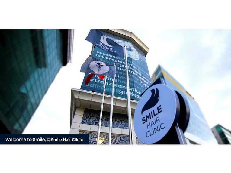 Exterior of the Smile Hair Clinic building with clinic signage and flags in Istanbul (press photo, Le Point).