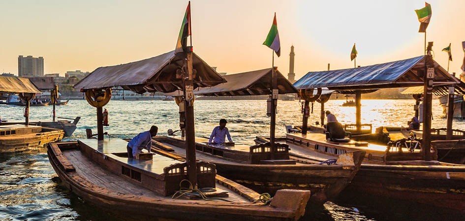 Traditional abra boats on Dubai Creek at sunset in old Deira